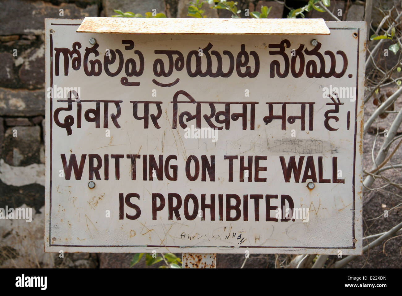 A multi-lingual sign in Golconda Fortress near Hyderabad India states that 'writting on the wall is prohibited'. Stock Photo