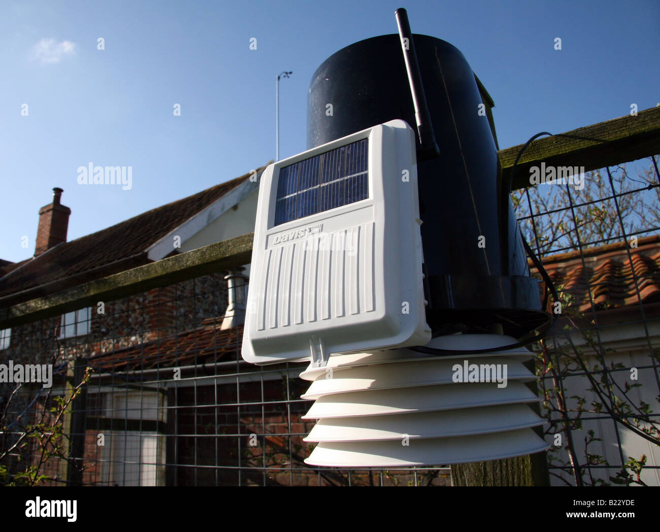 A solar powered Davis weather station mounted on the fence of a Suffolk cottage Stock Photo