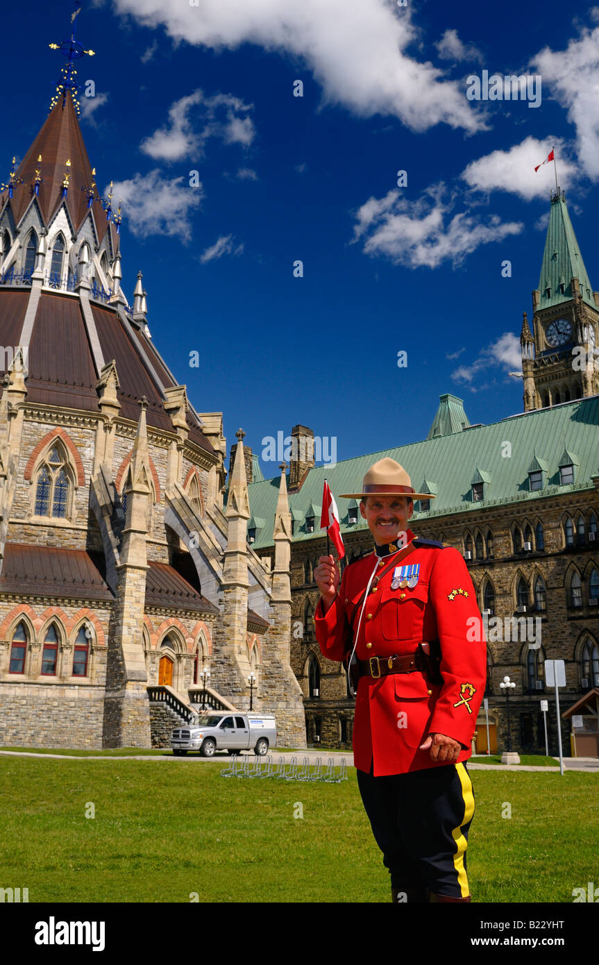 RCMP Royal Canadian Mounted Police officer holding flag at Parliament buildings Center Block and Library with Peace Tower in Ottawa Stock Photo