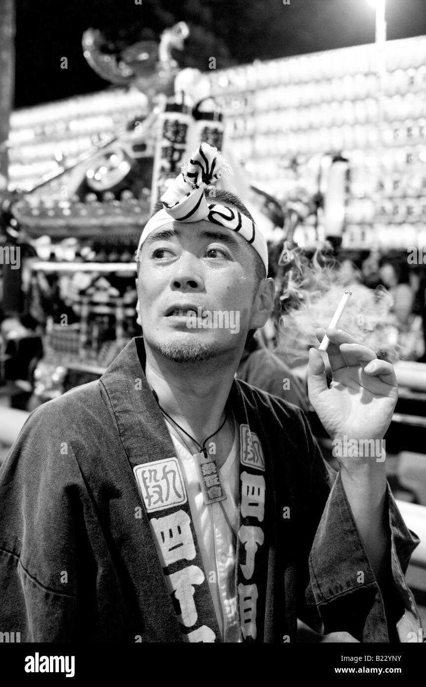 Japanese man in traditional costume smoking a cigarette at the Mitama Festival (Matsuri) in Tokyo, Japan Stock Photo