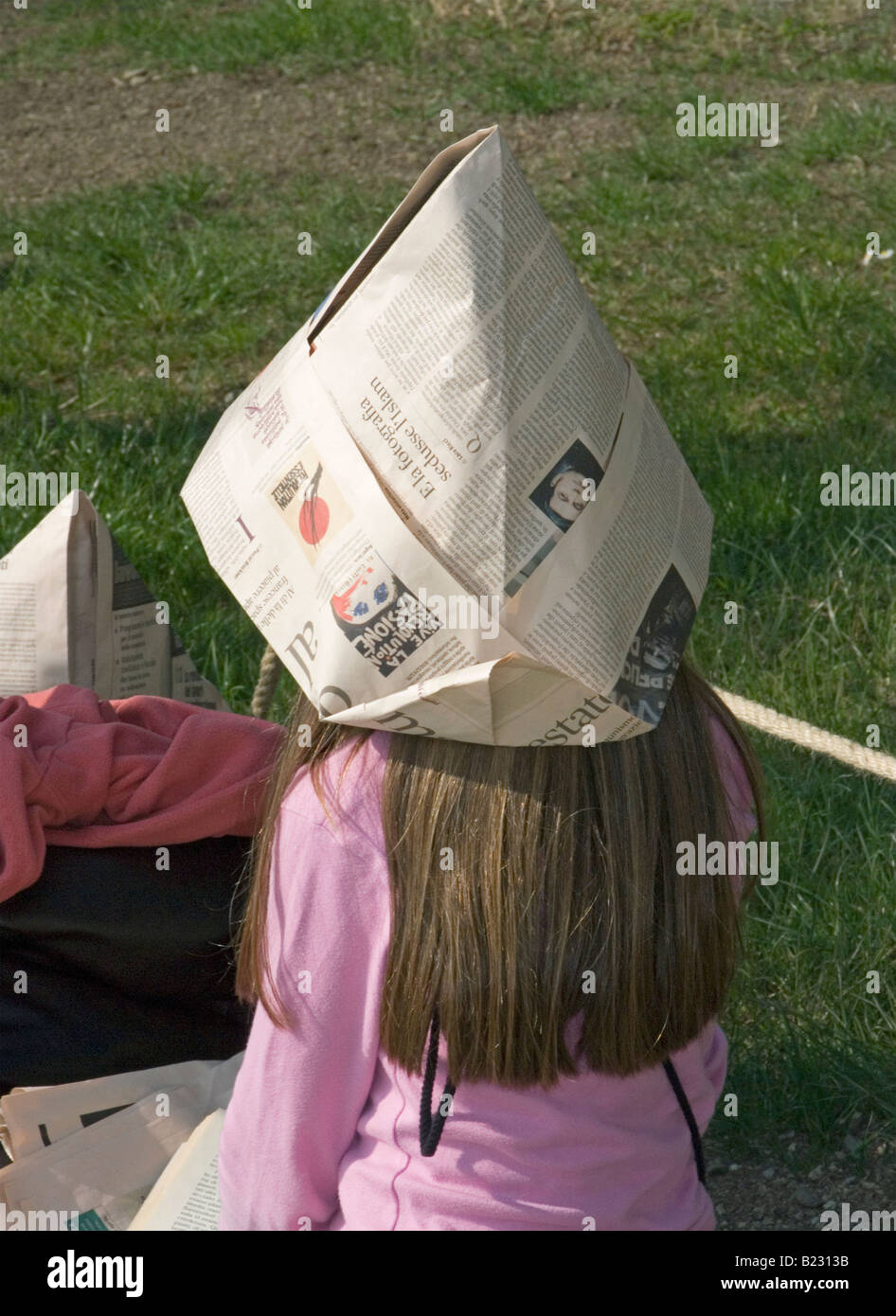 young girl wearing newspaper sunhat Stock Photo