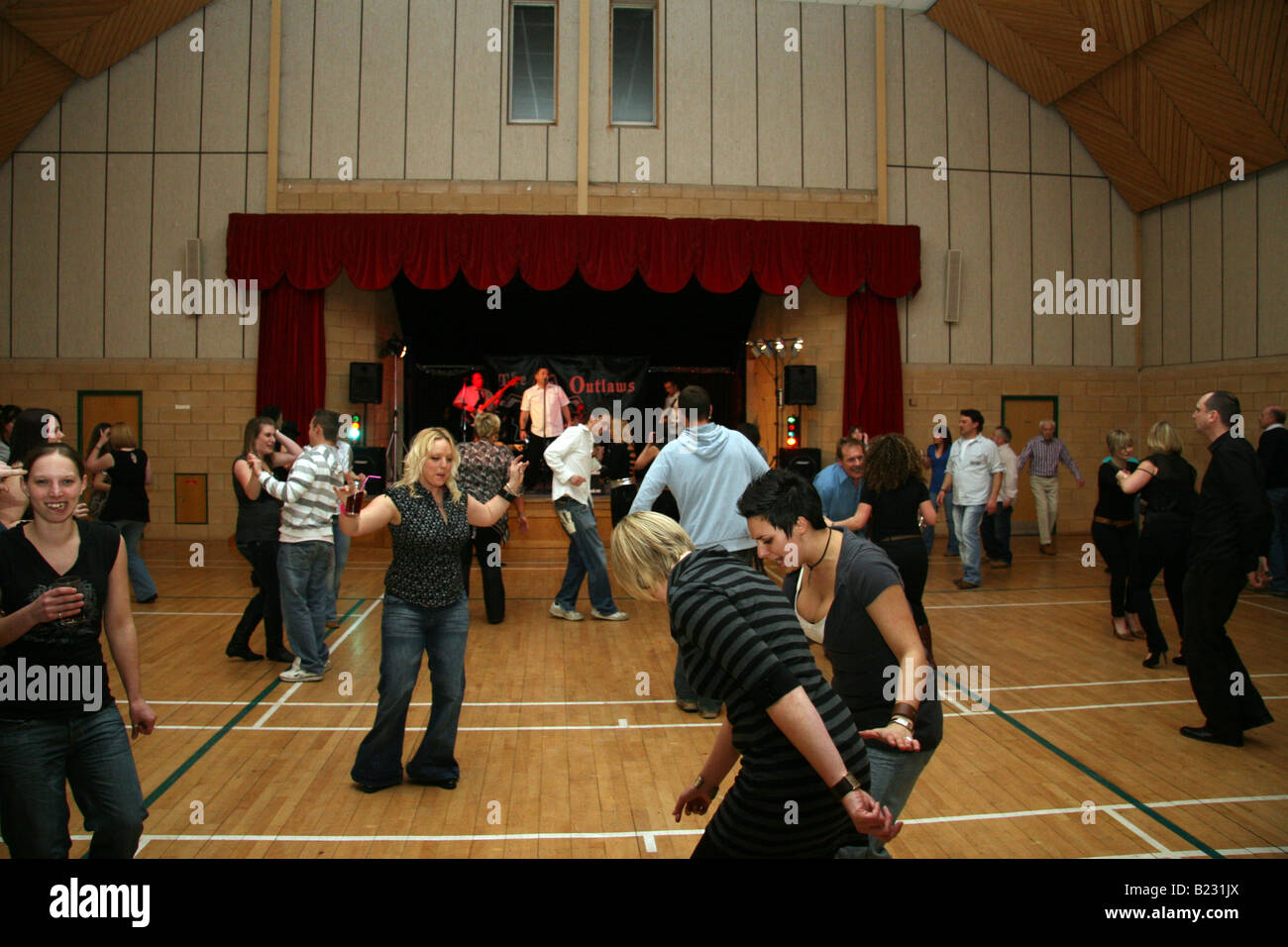 A mixed bunch of people dancing in a gymnasium to rock 'n roll band The Outlaws Stock Photo