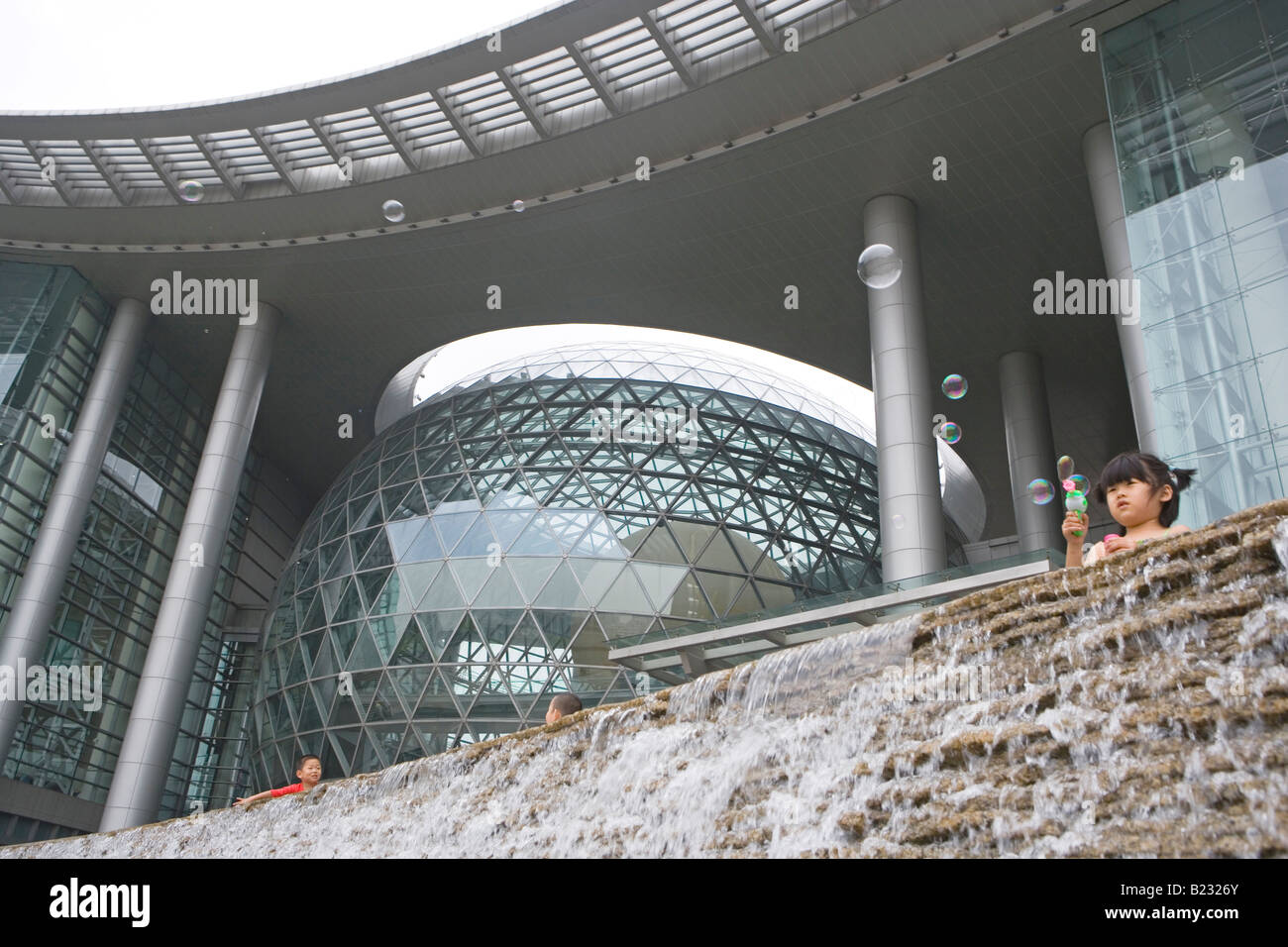 Low angle view of children near artificial waterfall in modern building Stock Photo