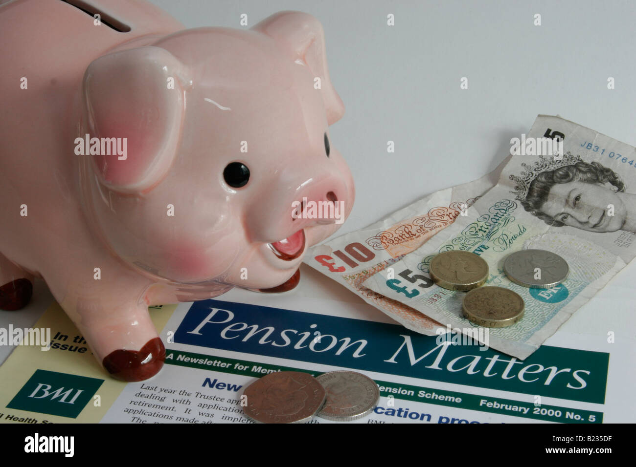 Typical company monthly pension news letter together with money and piggy bank. Stock Photo