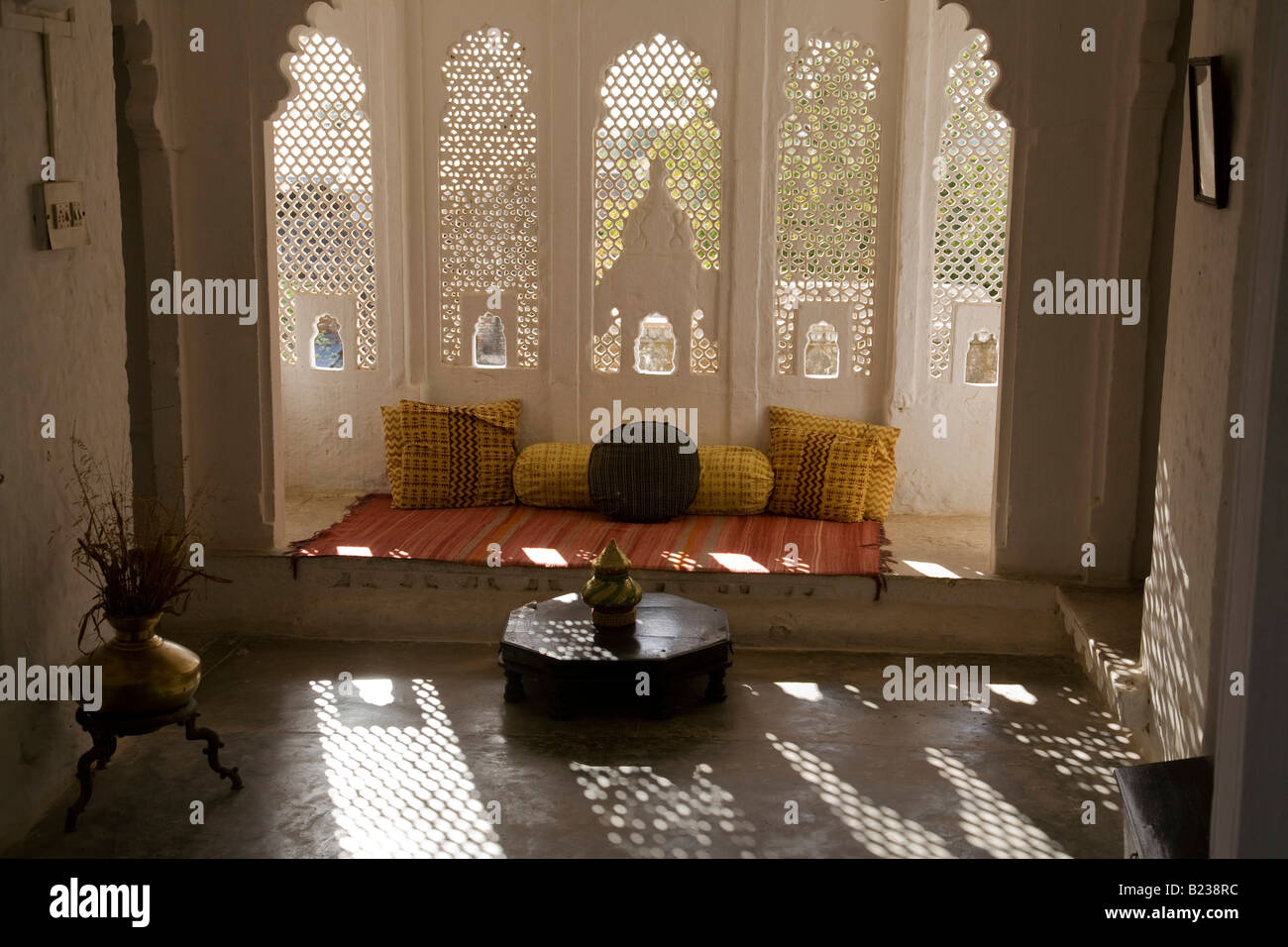 Screened window with sunlight flooding through to an Indian interior with window seating Stock Photo