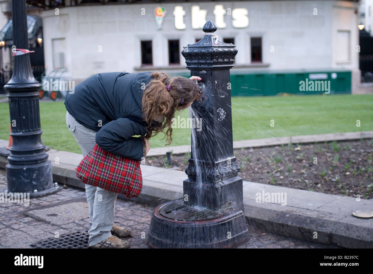 A woman drinks from a water fountain in London Stock Photo Alamy