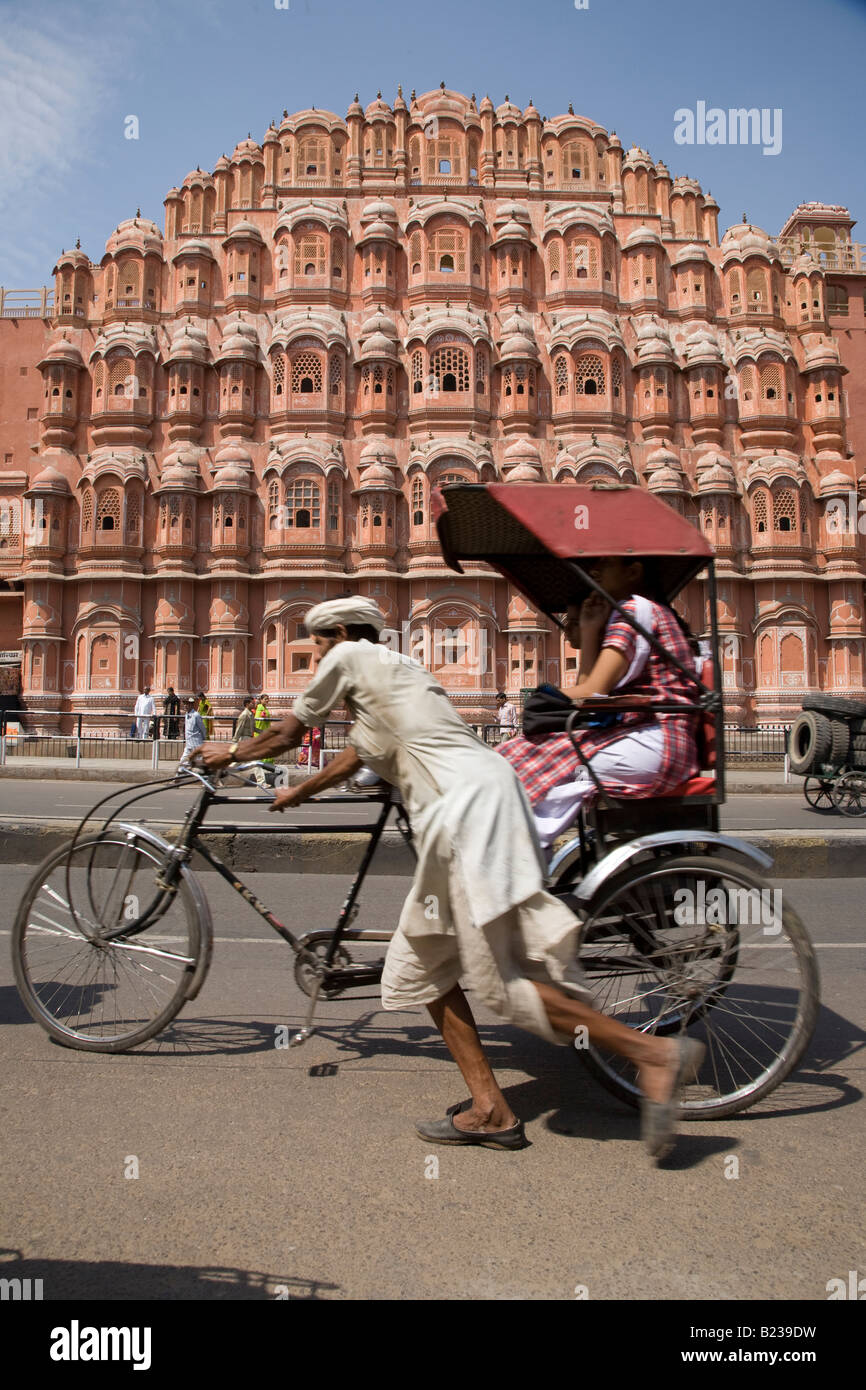 Tricycle rickshaw driver (wallah) pushes passengers along streeet in front of the Palace of the Winds in Jaipur Rajasthan India Stock Photo