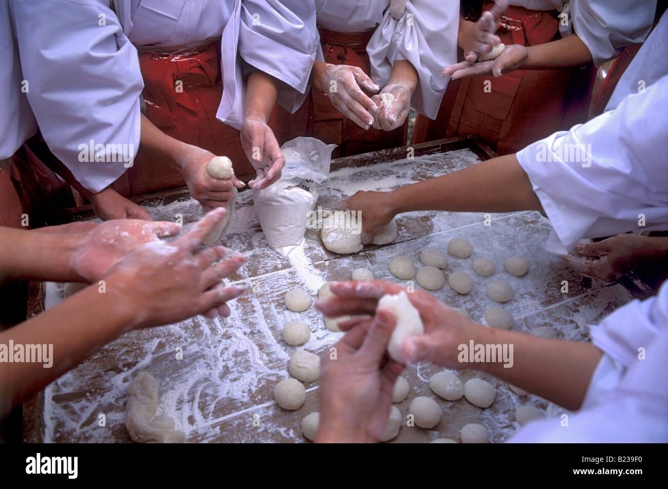 Shrine assistants called miko are making mochi balls from pounded rice paste during New Year festivities Stock Photo