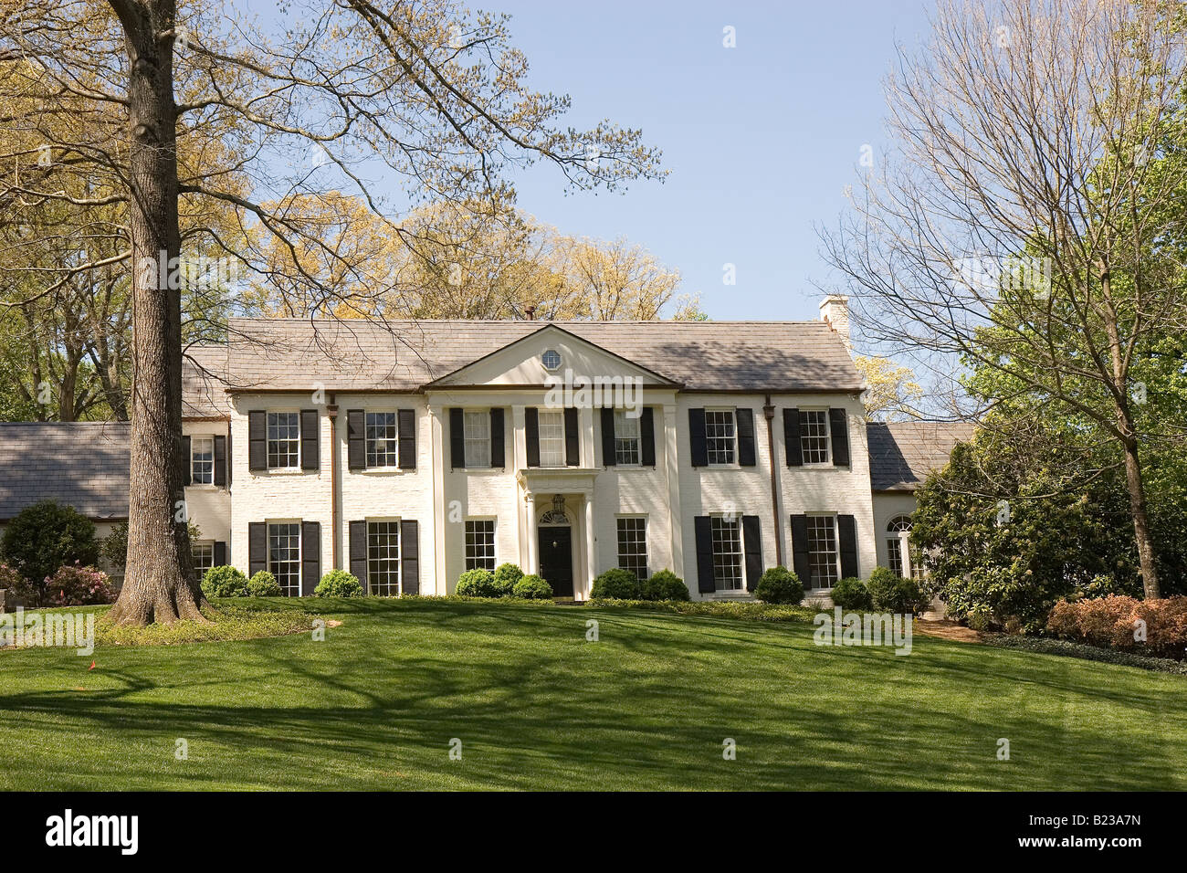 A large white house on a manicured green lawn and blue sky Stock Photo ...