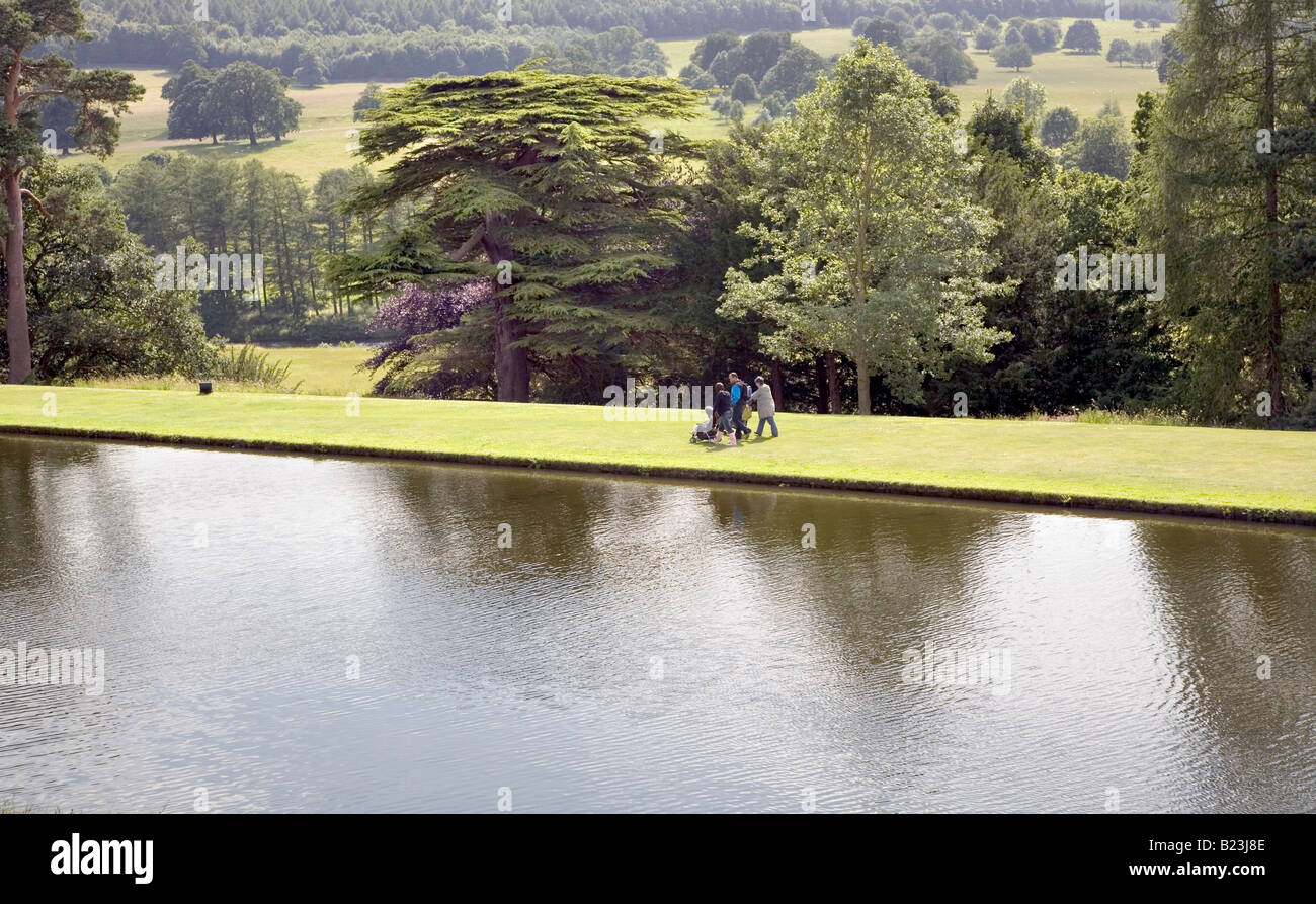 3 PEOPLE WALK ALONG THE LAKE AT HISTORIC CHATSWORTH HOUSE, OWNED BY The Duke and Duchess of Devonshire in the Derbyshire Peak Stock Photo