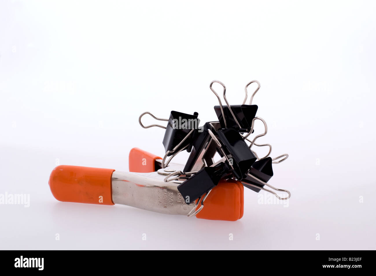 Black binder clips joined together atop a orange metal studio clip
