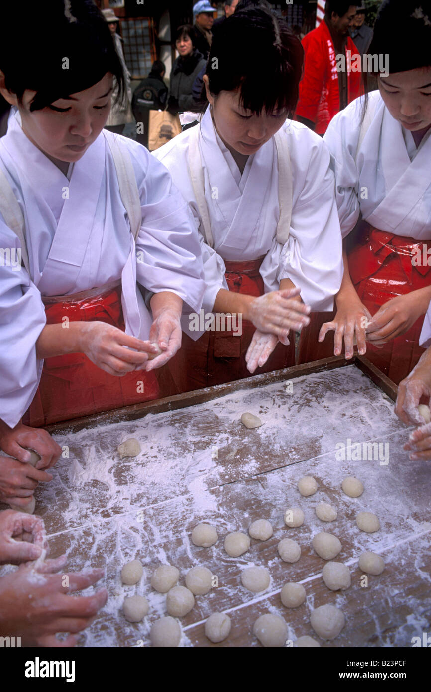 Shrine assistants called miko are making mochi balls from pounded rice paste during New Year festivities Stock Photo