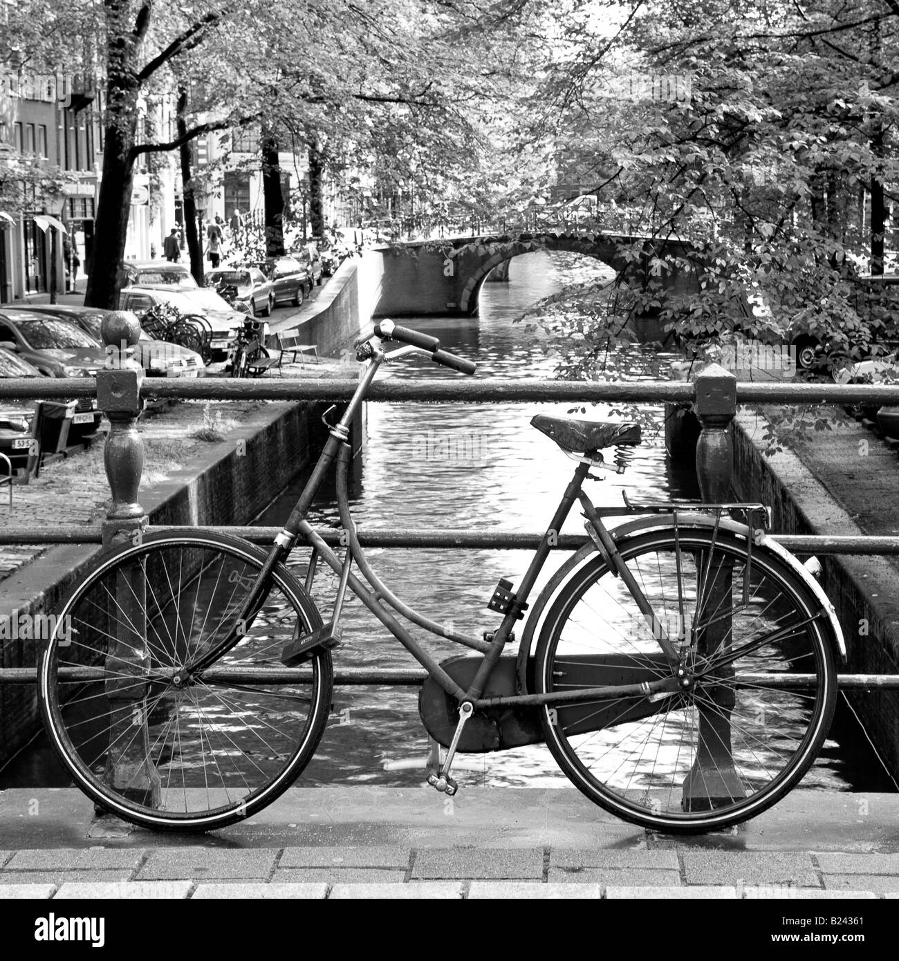 Bicyle Leaning Against Railings with Canal in monochrome black and white in Amsterdam North Holland Netherlands Stock Photo