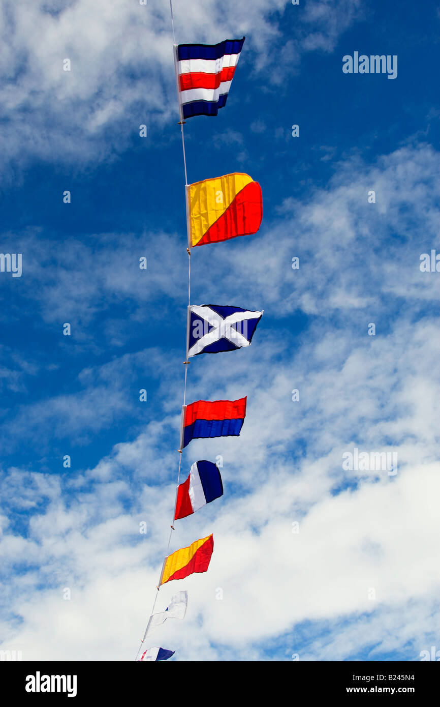 Bunting of flags of the world on display against a blue sky with white clouds at St Mawes harbour in Cornwall UK Stock Photo