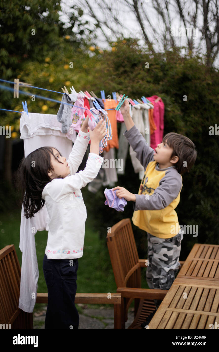 Hanging laundry on washing line to dry girl aged five and brother