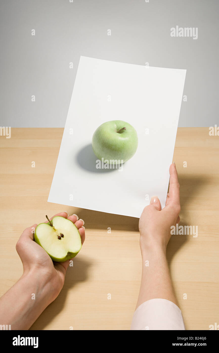 A woman holding a photograph of an apple Stock Photo