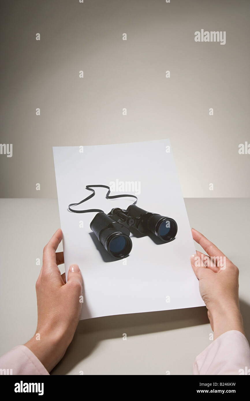 A woman holding a photograph of binoculars Stock Photo