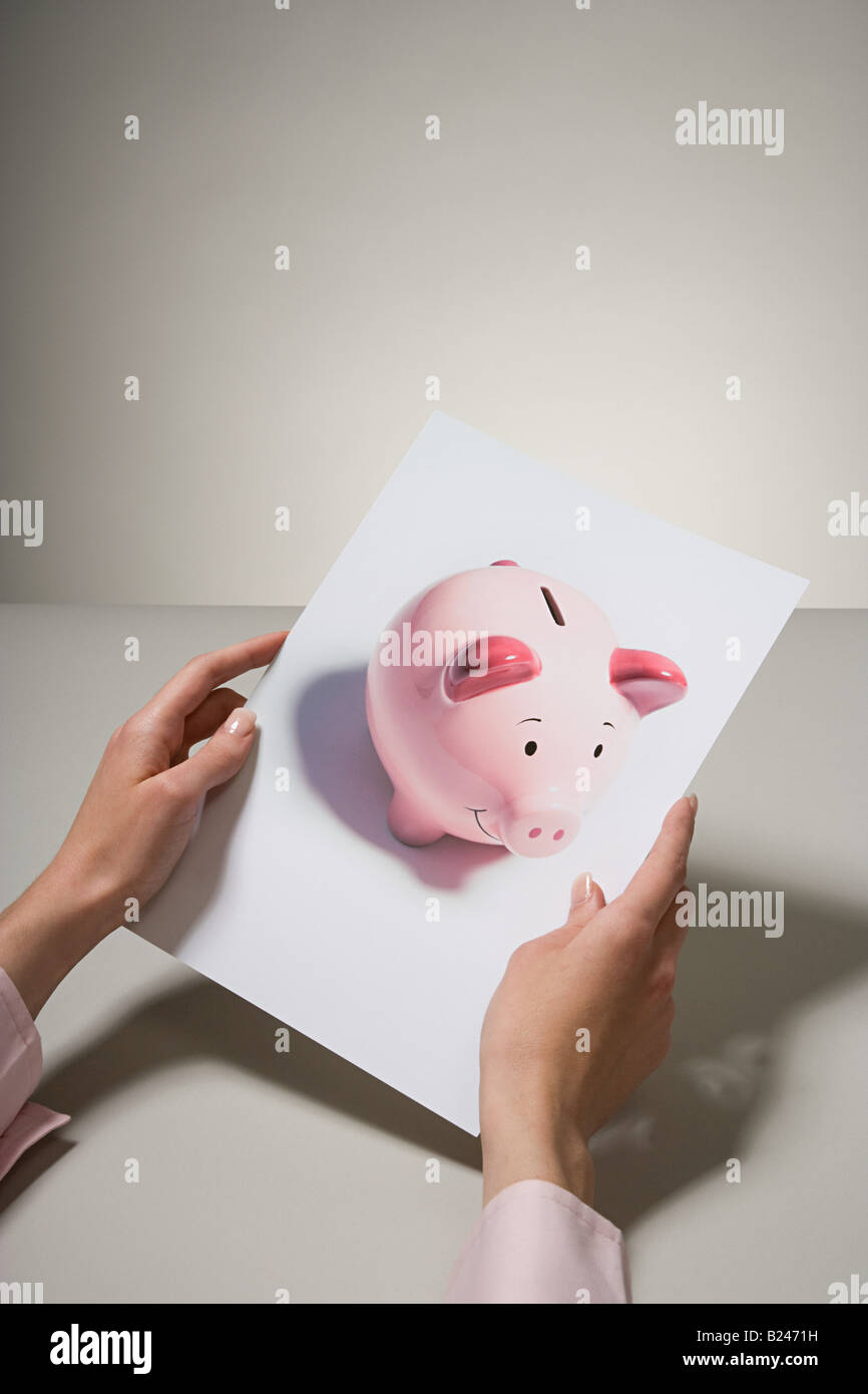 A woman holding a photograph of a piggy bank Stock Photo - Alamy