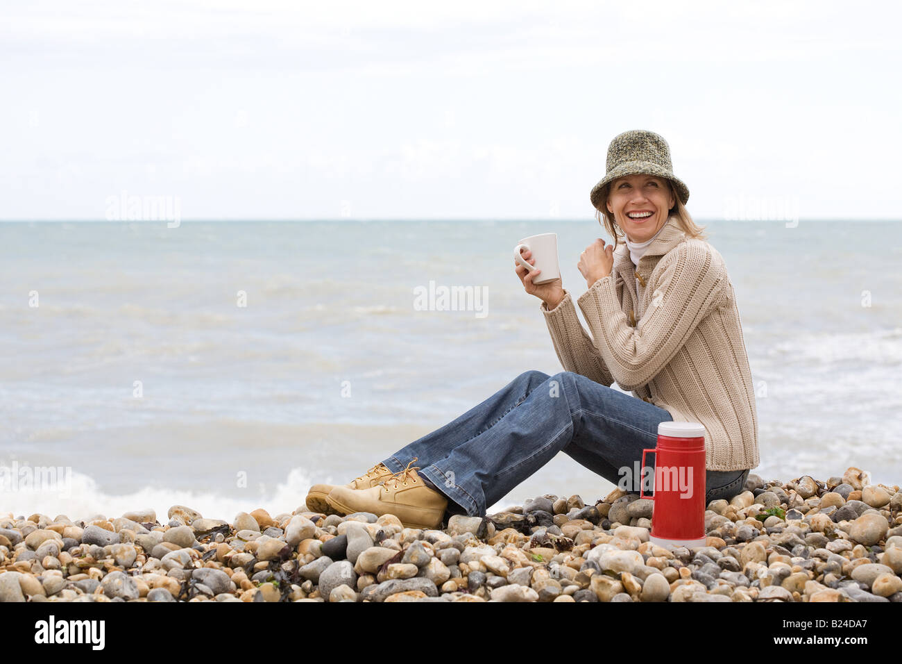 Woman having a drink at the beach Stock Photo