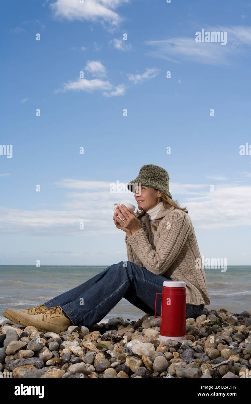 Woman having a drink on the beach Stock Photo