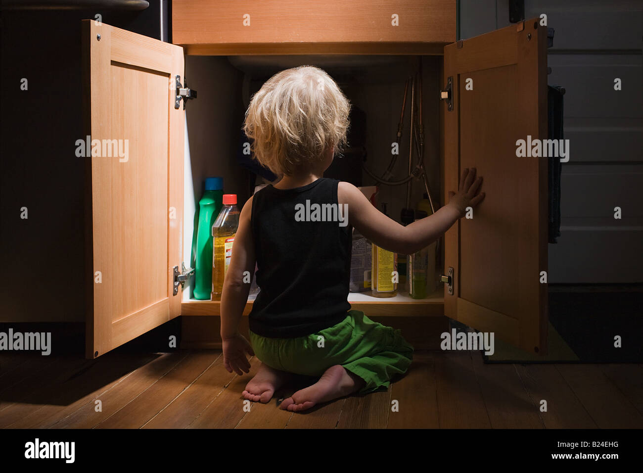 Little boy opening cupboard of cleaning products Stock Photo