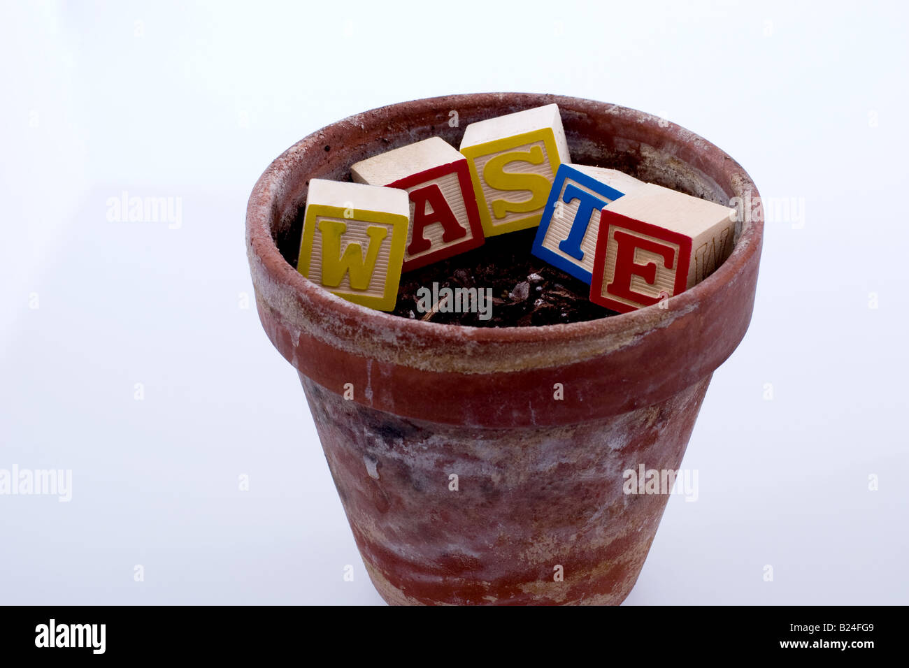 Empty barren flower pot with the word 'waste' spelled out in blocks Stock Photo