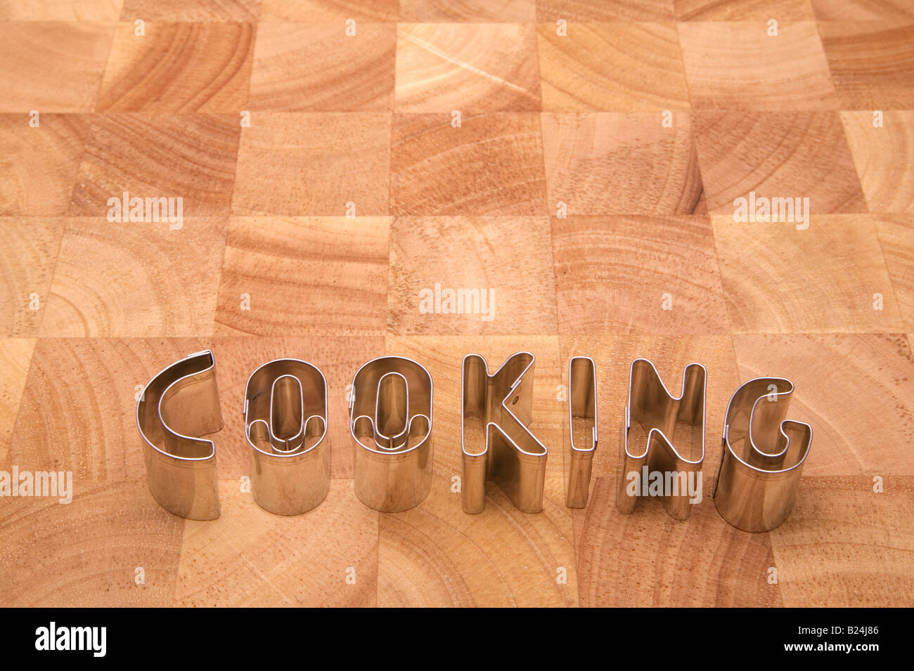 Cooking spelt using metal letters on a wooden block chopping board Stock Photo
