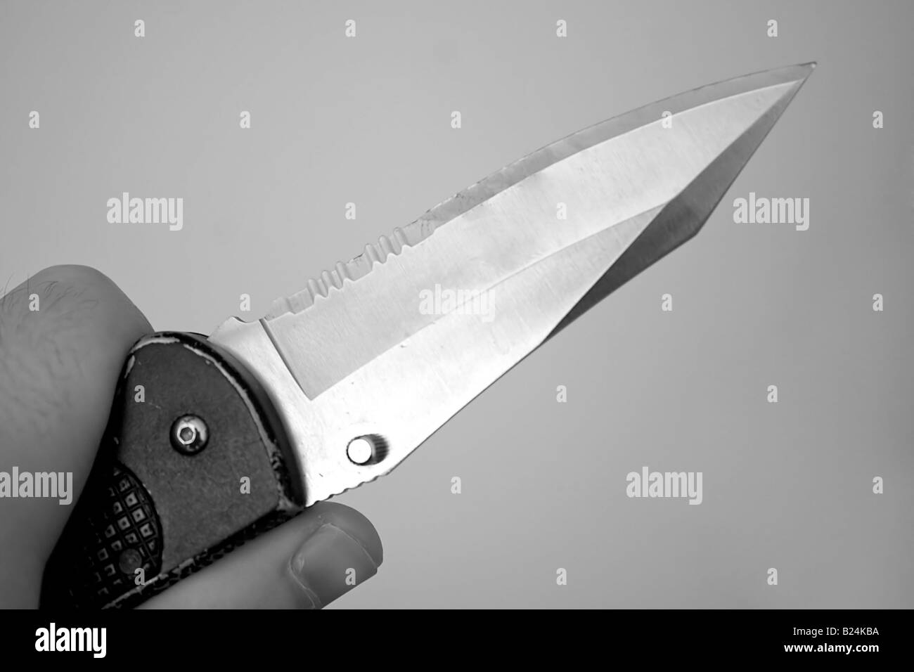 Closeup of a hand holding a knife with a sharp blade Stock Photo