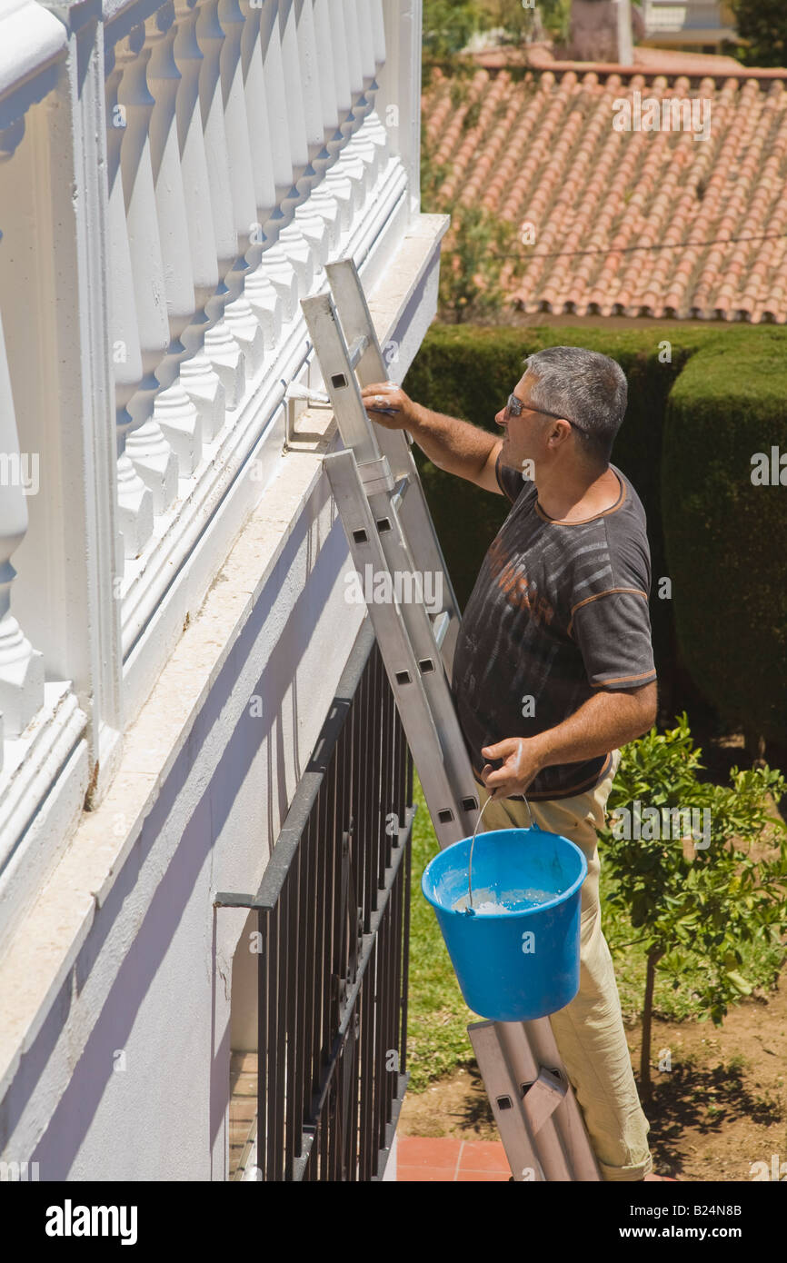 Man in Spain standing on ladder painting Stock Photo