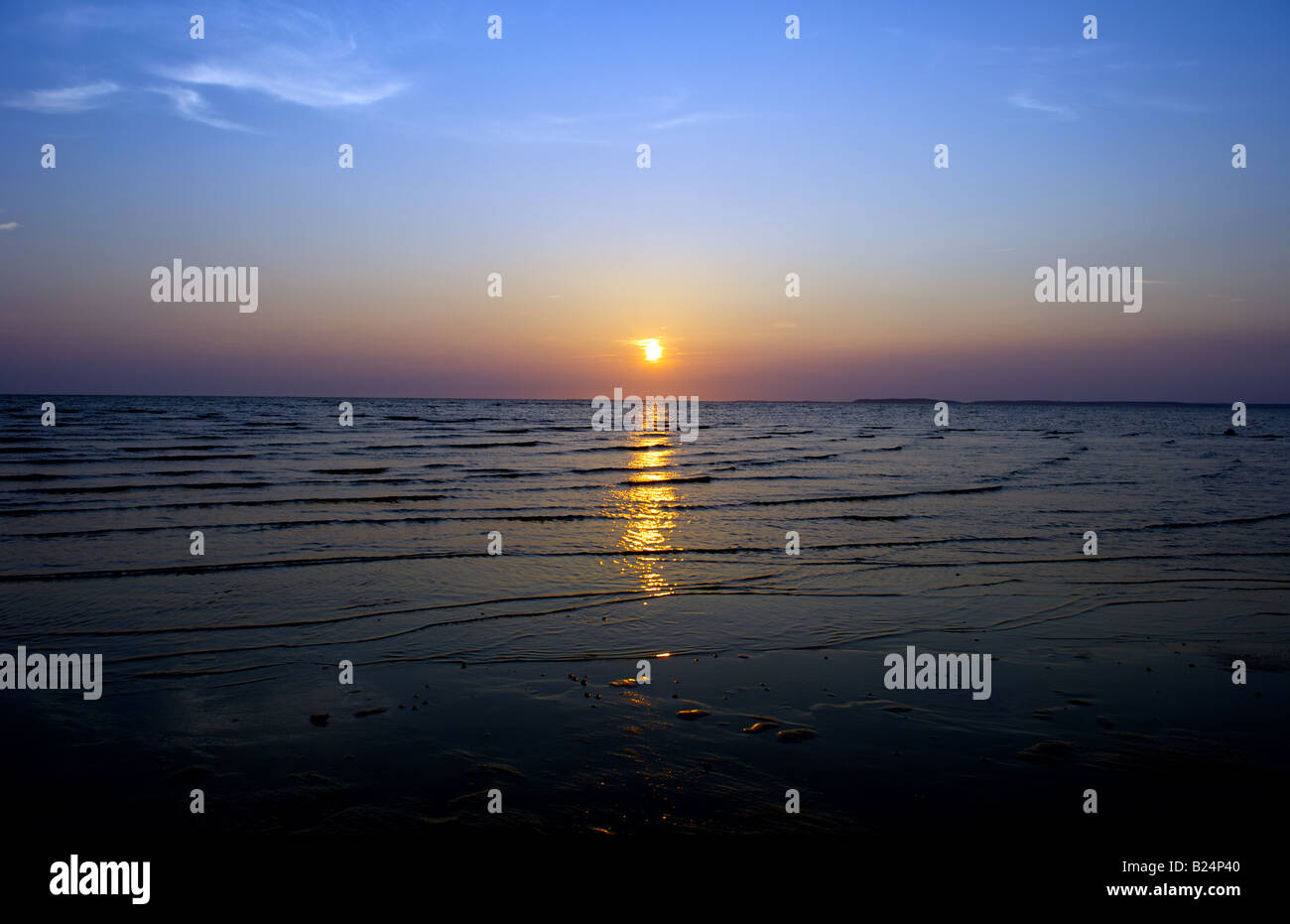 sun setting above the water with reflections in water Stock Photo - Alamy