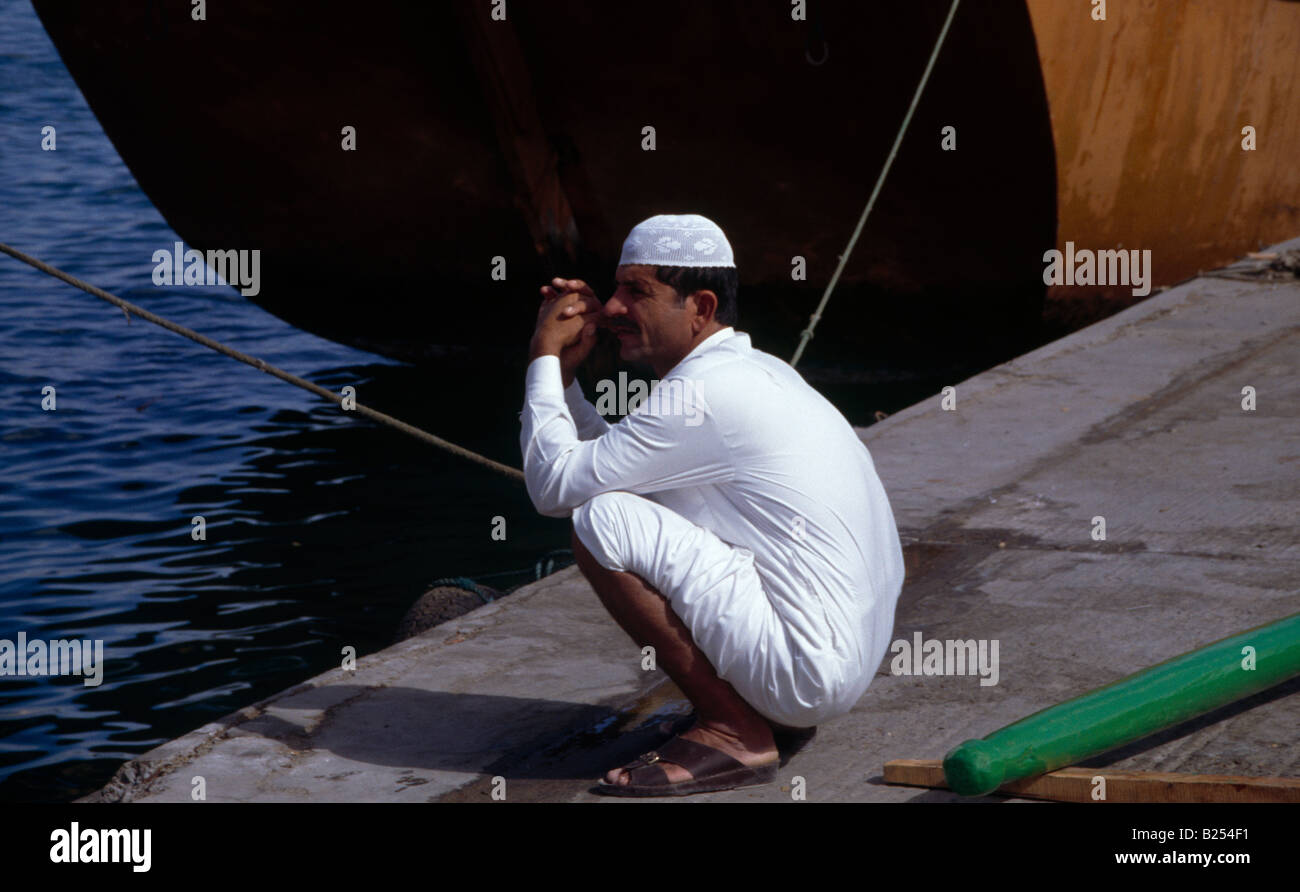Sharjah UAE Creek with Dhow and Man Crouching Stock Photo