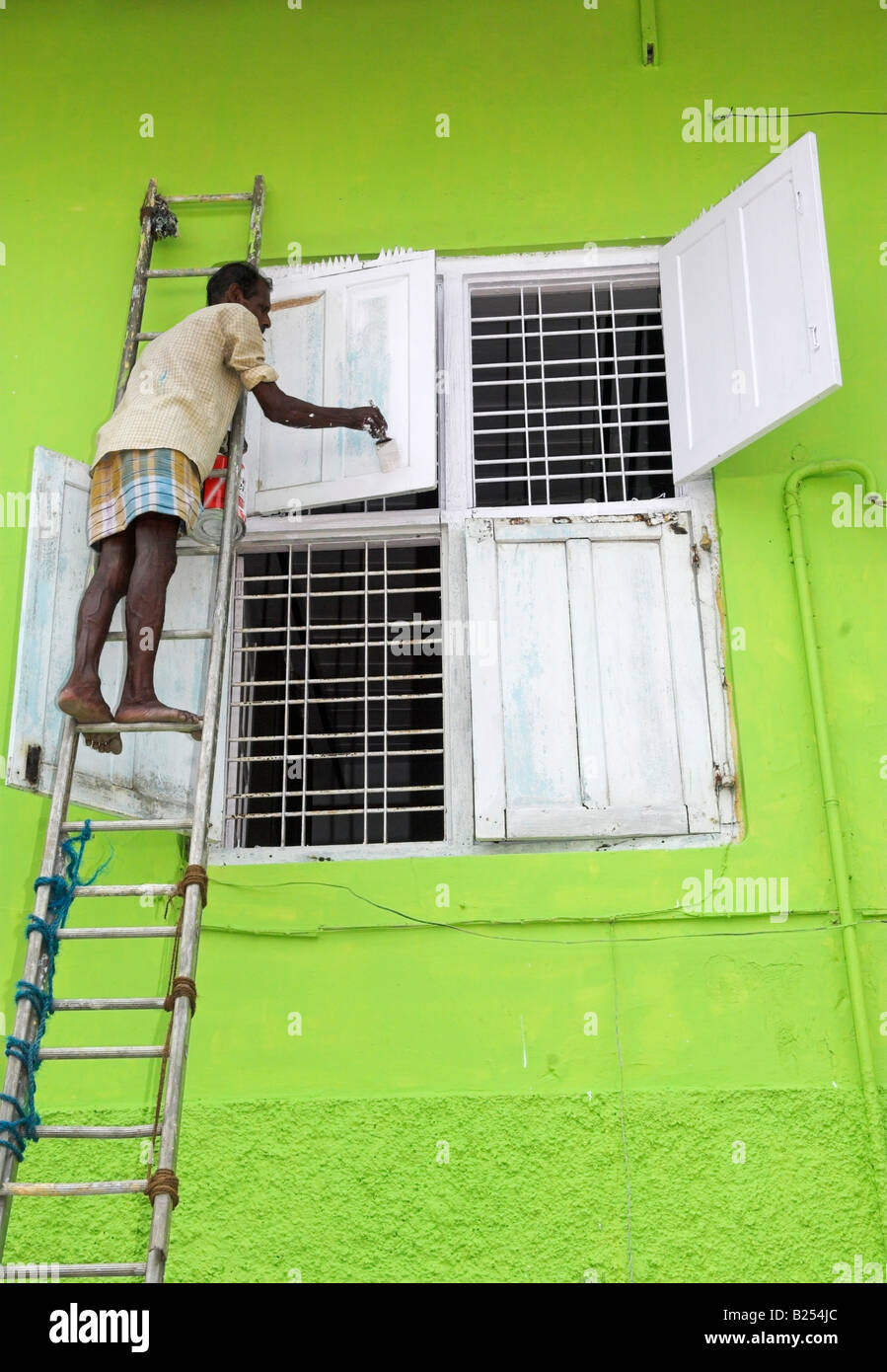 Man on top of ladder painting house windows Stock Photo - Alamy