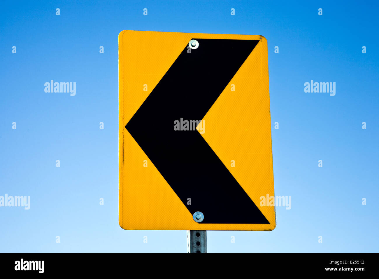 Black Arrow On Yellow Traffic Sign Pointing Left On Blue Sky Stock