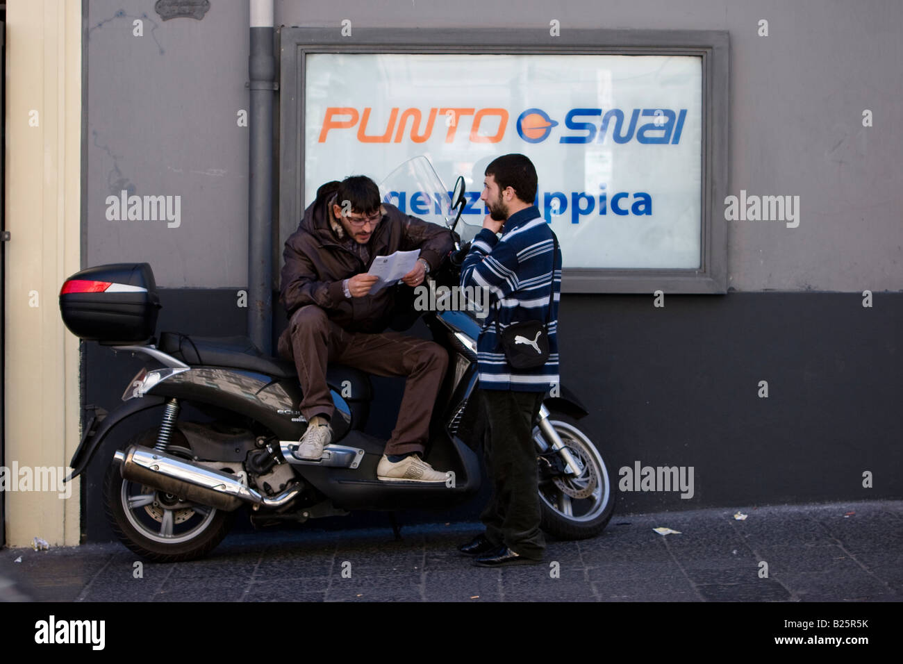 Two men outside an betting office in Catania, Sicily, Italy Stock Photo