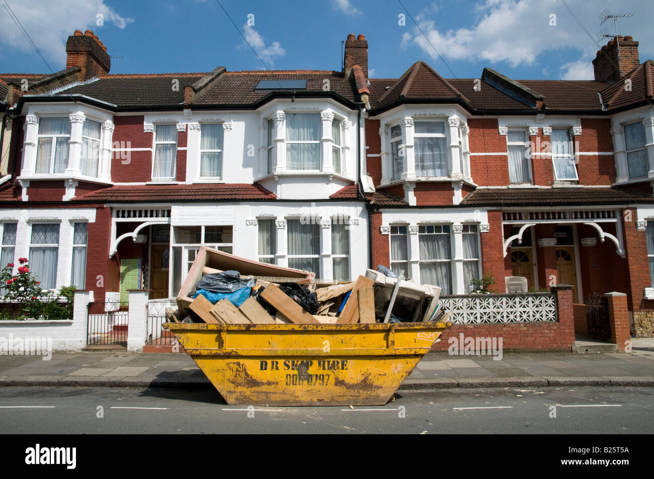 Yellow skip in residential street in London England UK Stock Photo