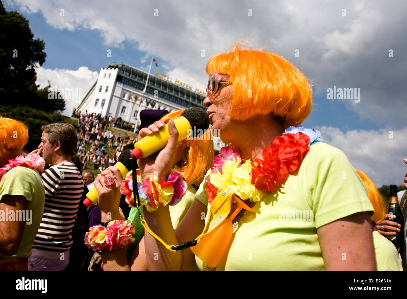 Woman wearing an orange wig sings into a toy microphone celebrate a german country music party the Schlagermove in Hamburg Stock Photo