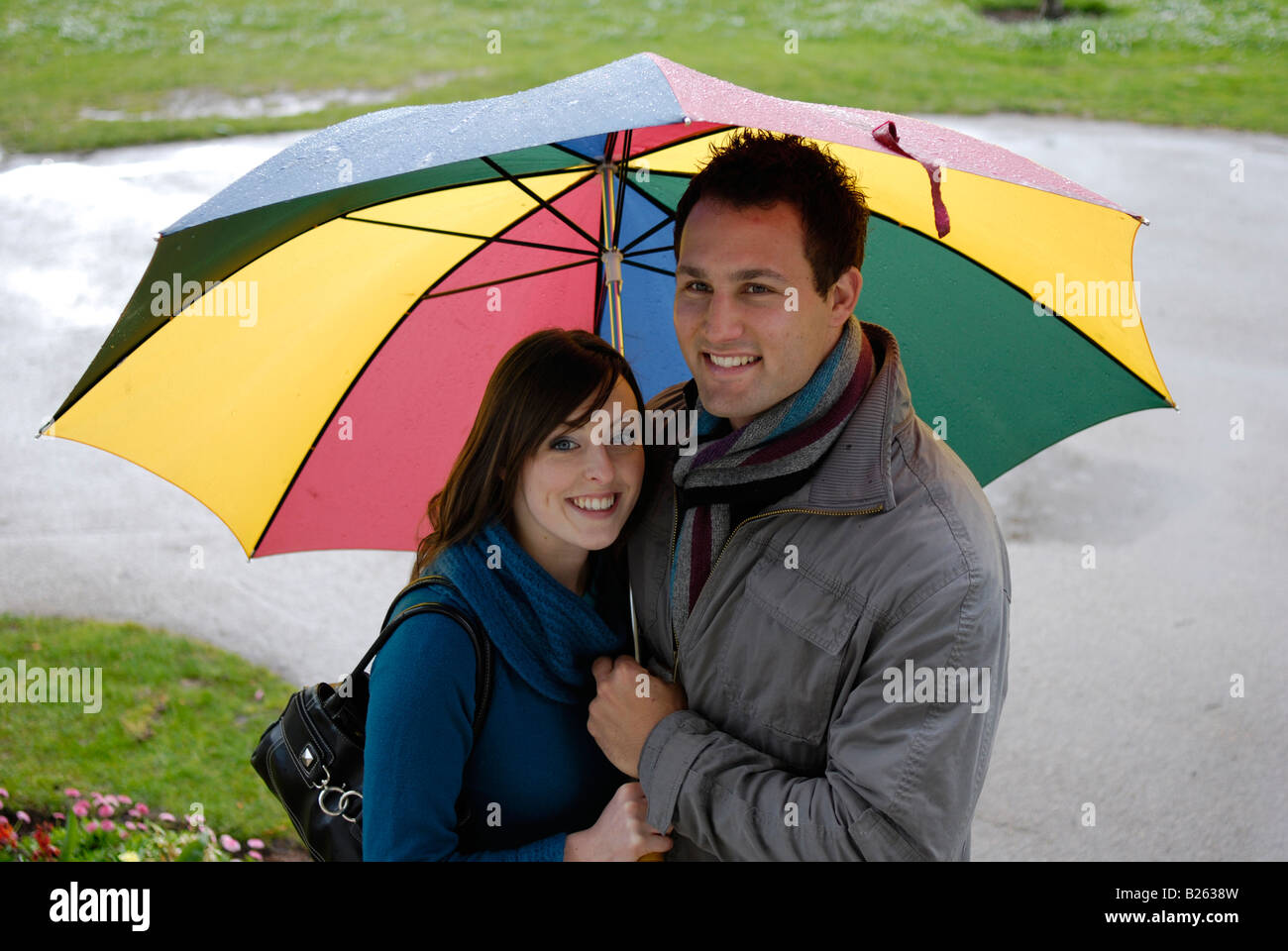 A happy young couple shelter form the rain under a large umbrella Stock ...