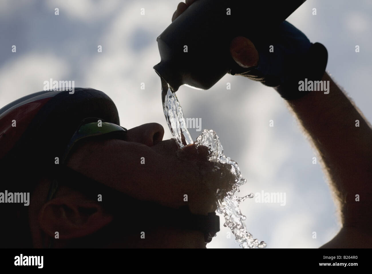 Silhouetted of a cyclist drinking water, side view Stock Photo