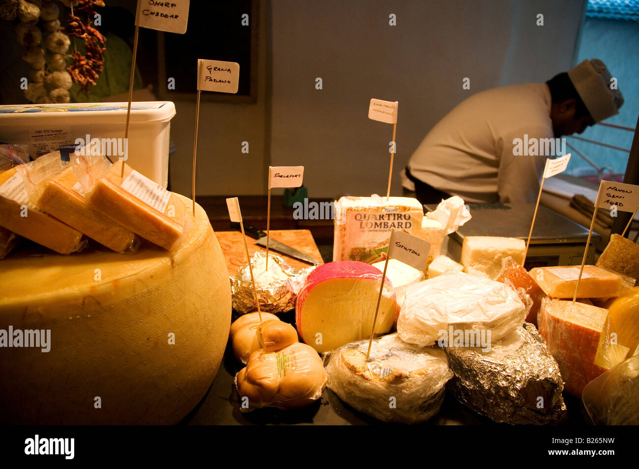 Cheeses are offered for sale in a delicatessen. This shop is based in