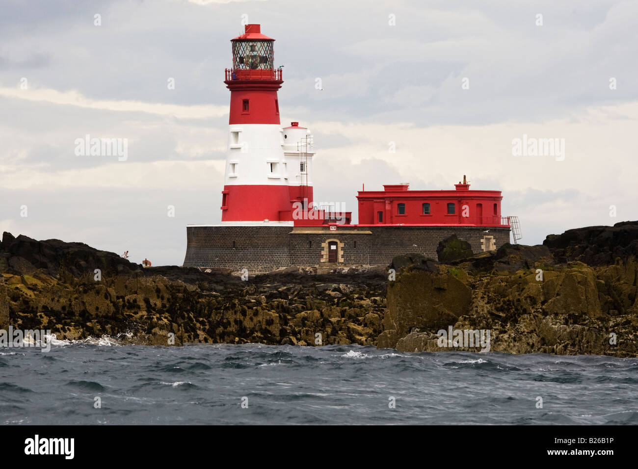 Longstone Lighthouse on seaside against cloudy sky. Stock Photo