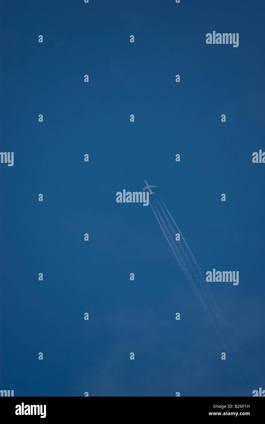 A jet with contrail showing four separate streaks on the sky Stock Photo