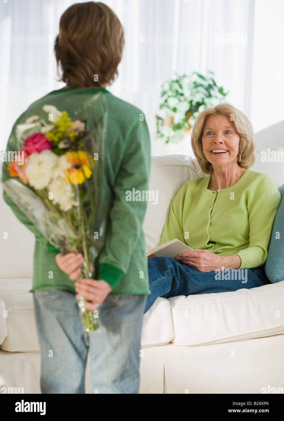 Grandson surprising grandmother with flowers Stock Photo