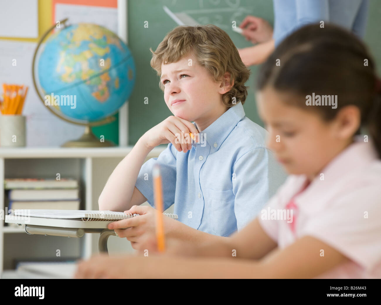 Boy thinking at school desk Stock Photo