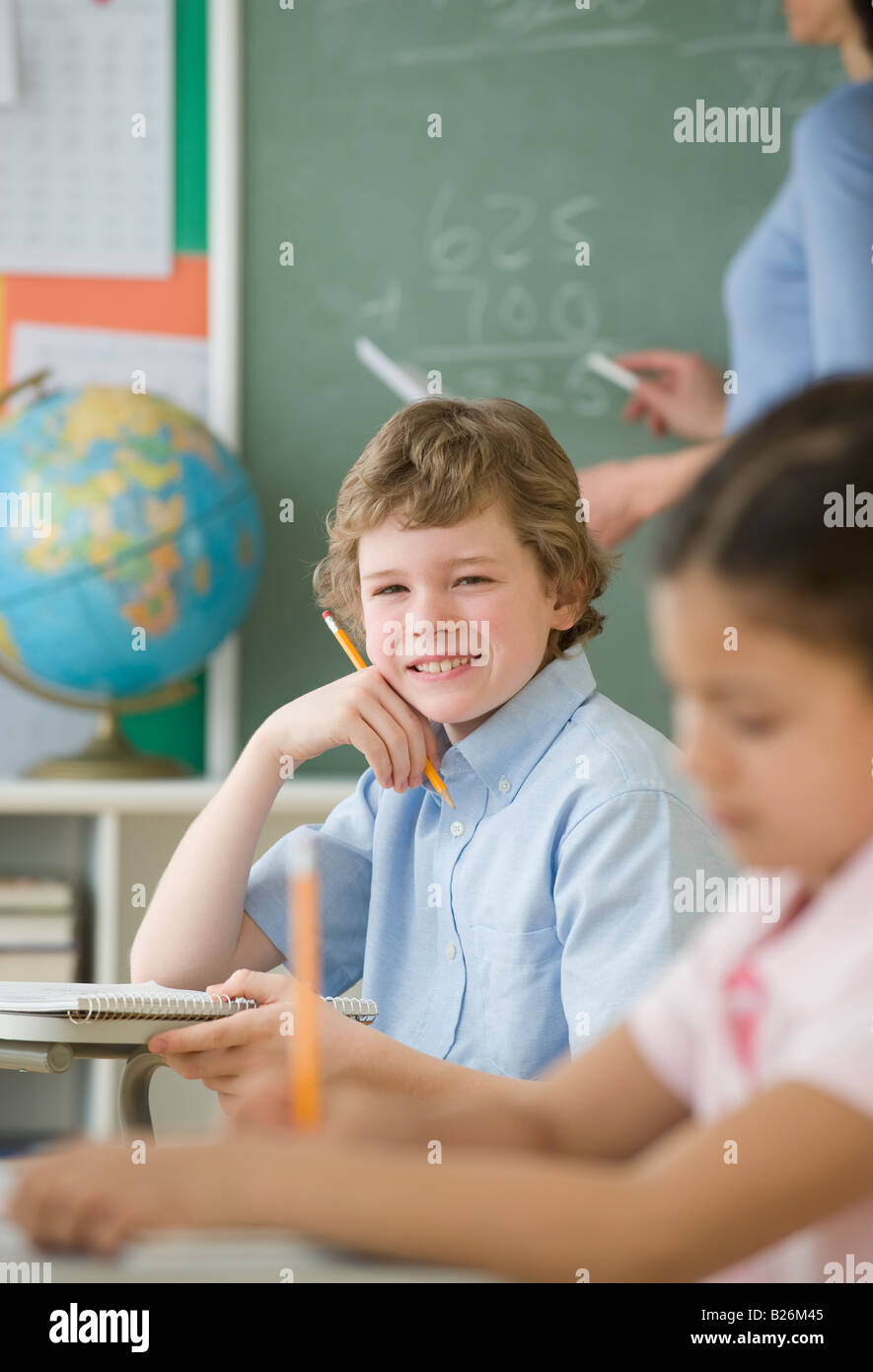 Boy holding pencil at school desk Stock Photo