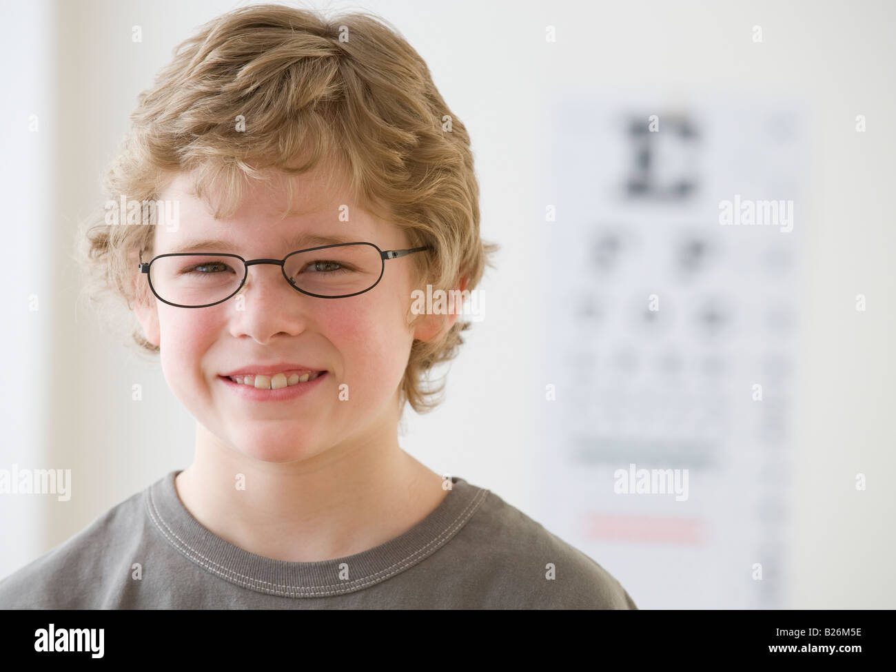 Boy wearing eyeglasses in front of eye chart Stock Photo