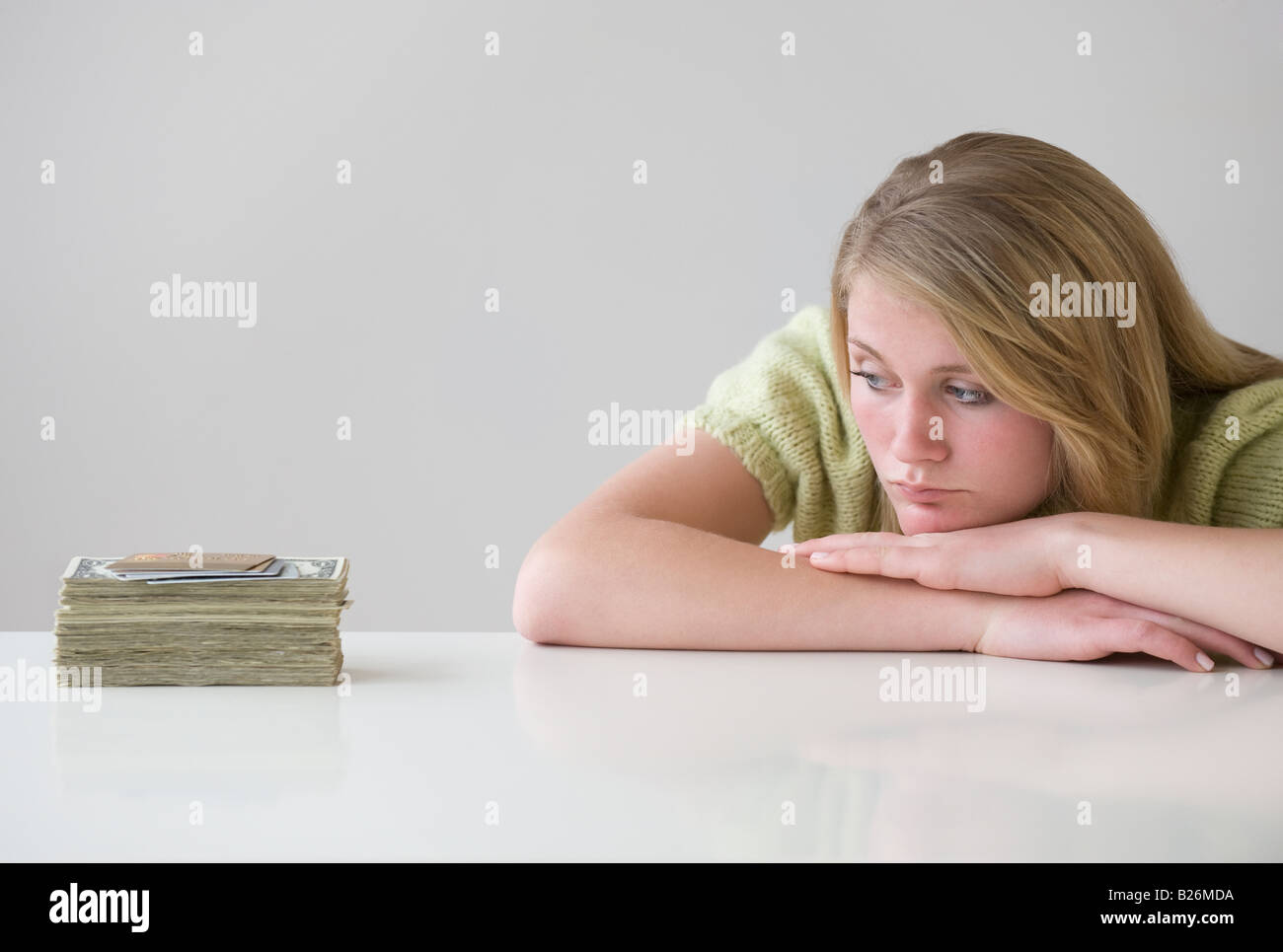 Teenaged girl looking at stack of money Stock Photo