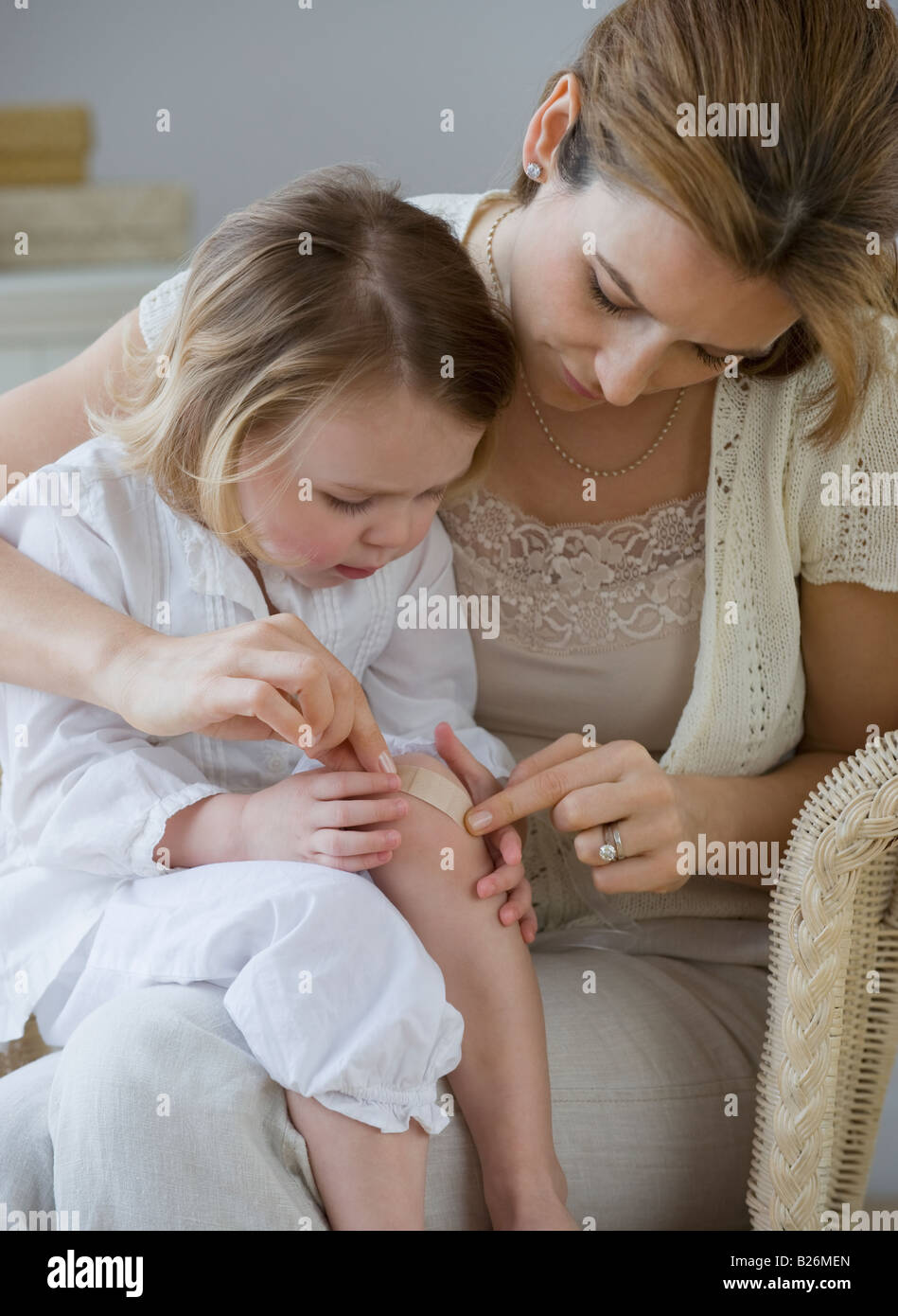 Mother putting bandage on daughter’s knee Stock Photo