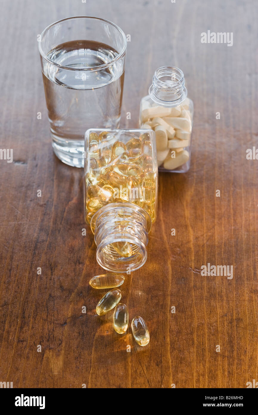 Vitamins in bottles next to water Stock Photo