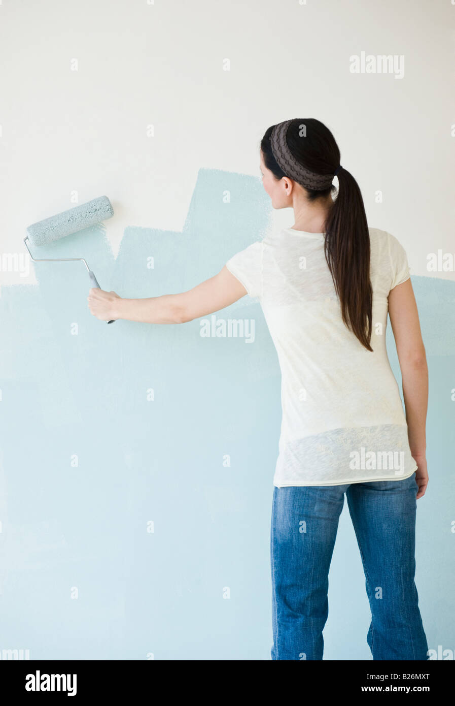 Woman painting wall with paint roller Stock Photo