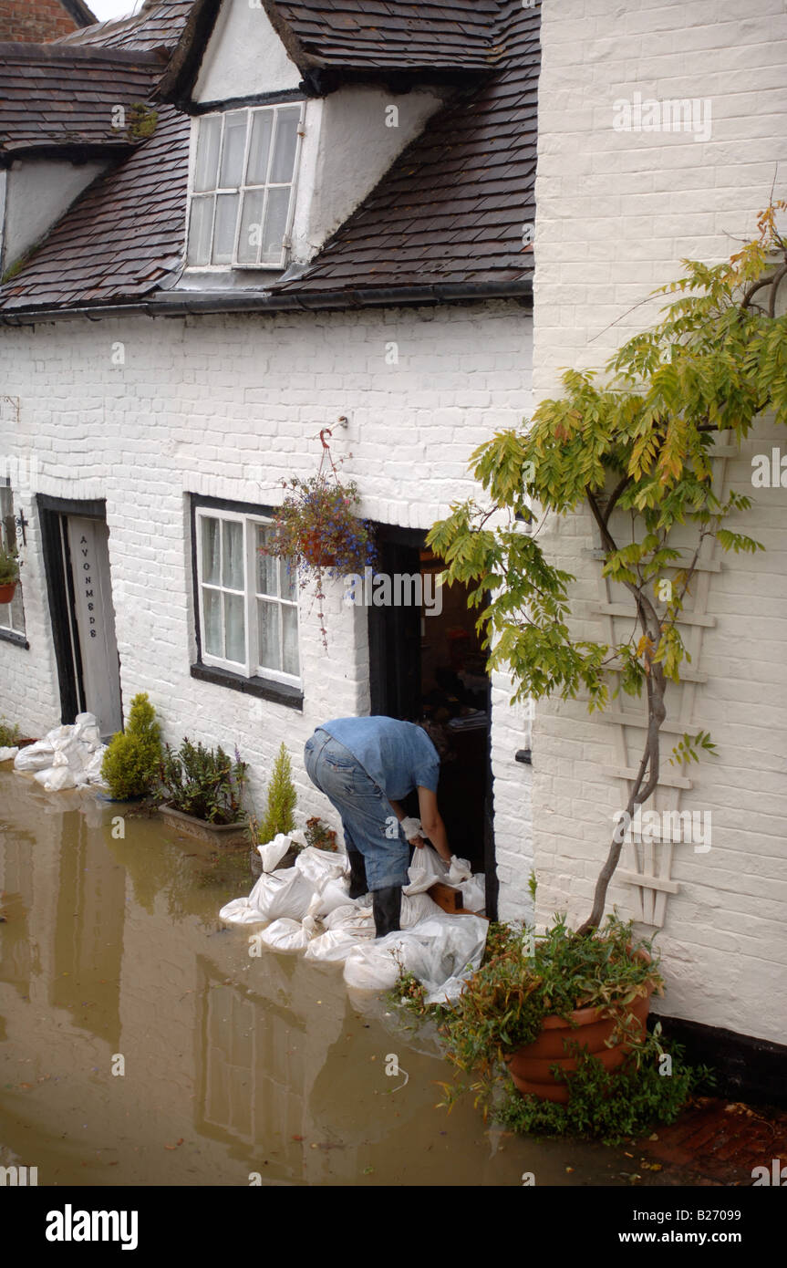 A RESIDENT OF FLOOD STRICKEN TEWKESBURY GLOUCESTERSHIRE BARRICADES THE FRONT DOOR OF A COTTAGE WITH SANDBAGS JULY 2007 UK Stock Photo